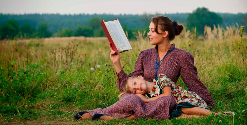 Женщина с дочкой читают на природе